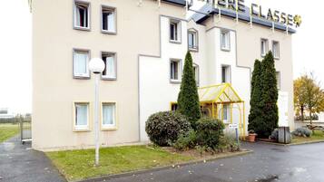 Ein Hotel namens "HOTEL PREMIERE CLASSE" mit moderner Fassade, zahlreichen Fenstern und einem gepflegten Rasenbereich.