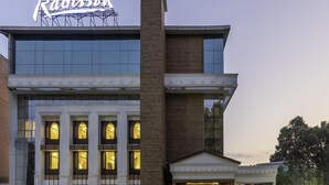 Un edificio con un letrero llamativo de 'Radisson', amplias ventanas y una chimenea de ladrillo.