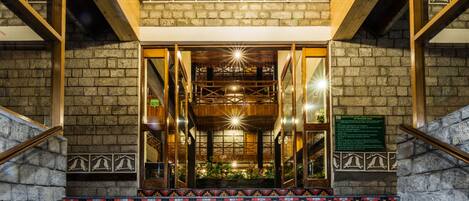 A building entrance with a tiled staircase, wooden beams, and a brick wall.