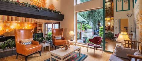 A spacious lobby with leather armchairs, a coffee table, and a large window offering a view of the outdoors.