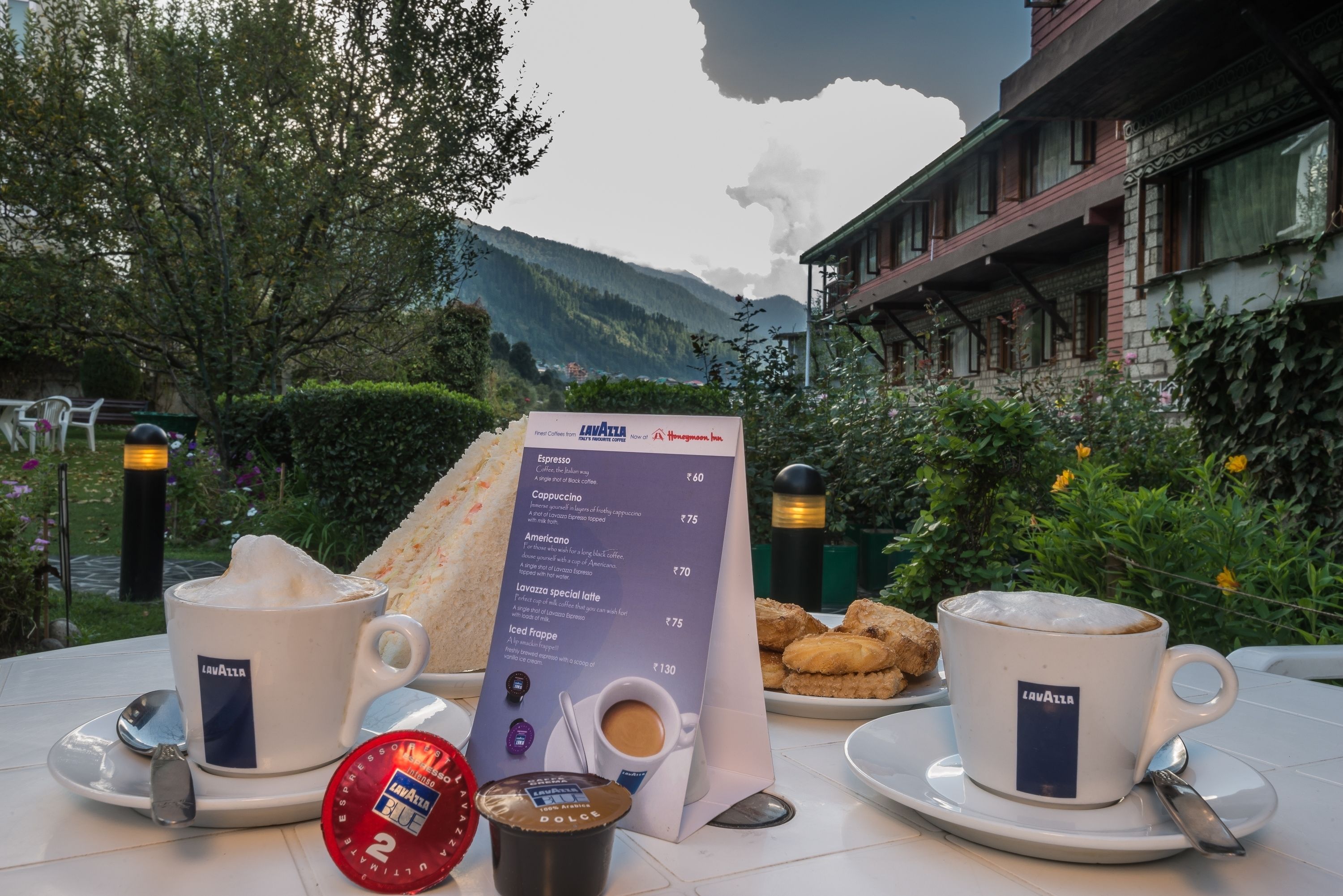 A table with two cups of coffee, a menu, and a dessert item.