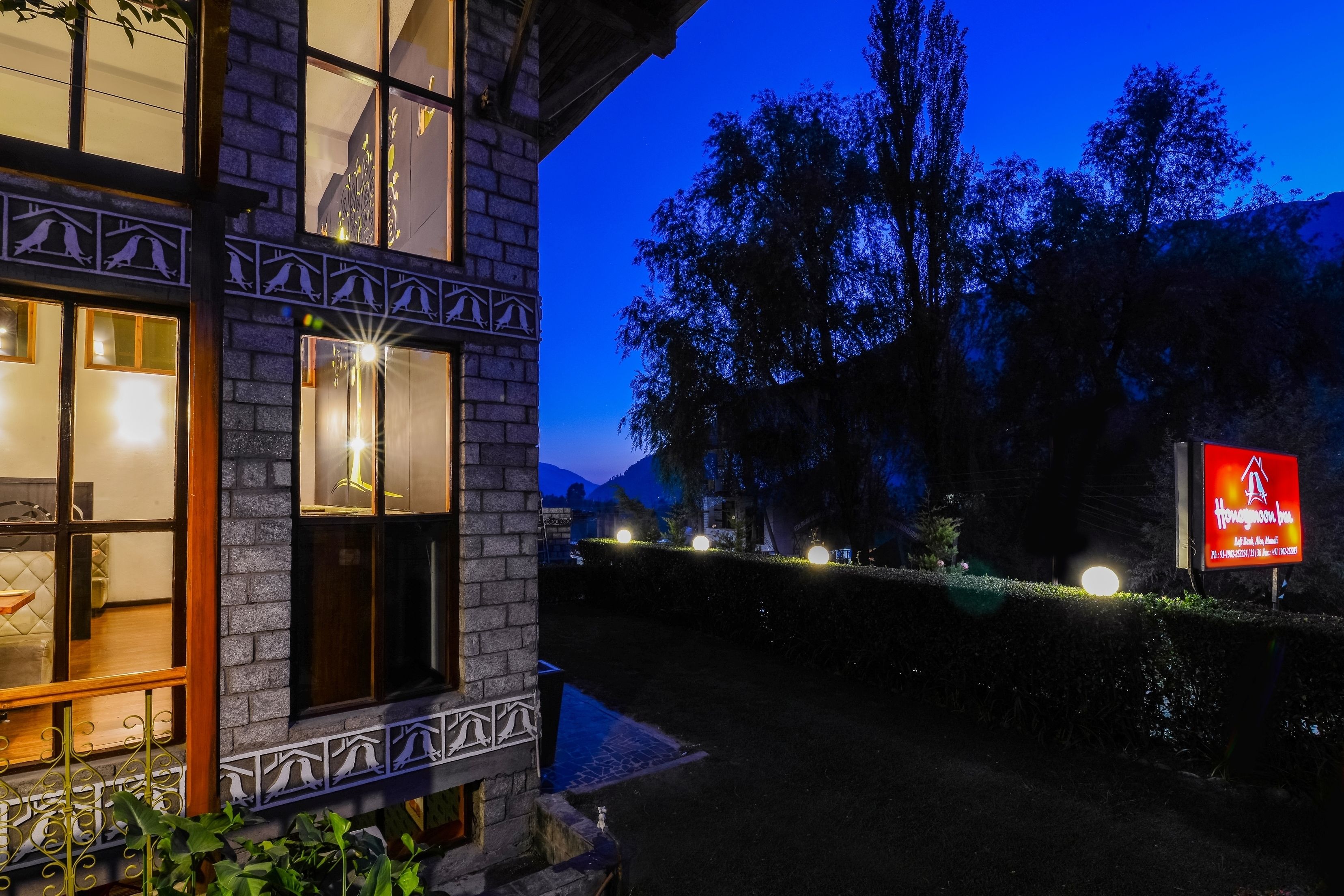A hotel with a stone facade, large windows, and a well-lit entrance.