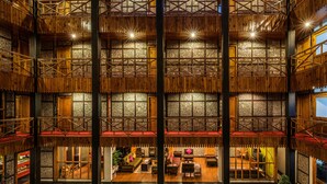 A multi-level wooden interior with balconies, a central seating area, and a view of the outside. - Honeymoon Inn (Manali)