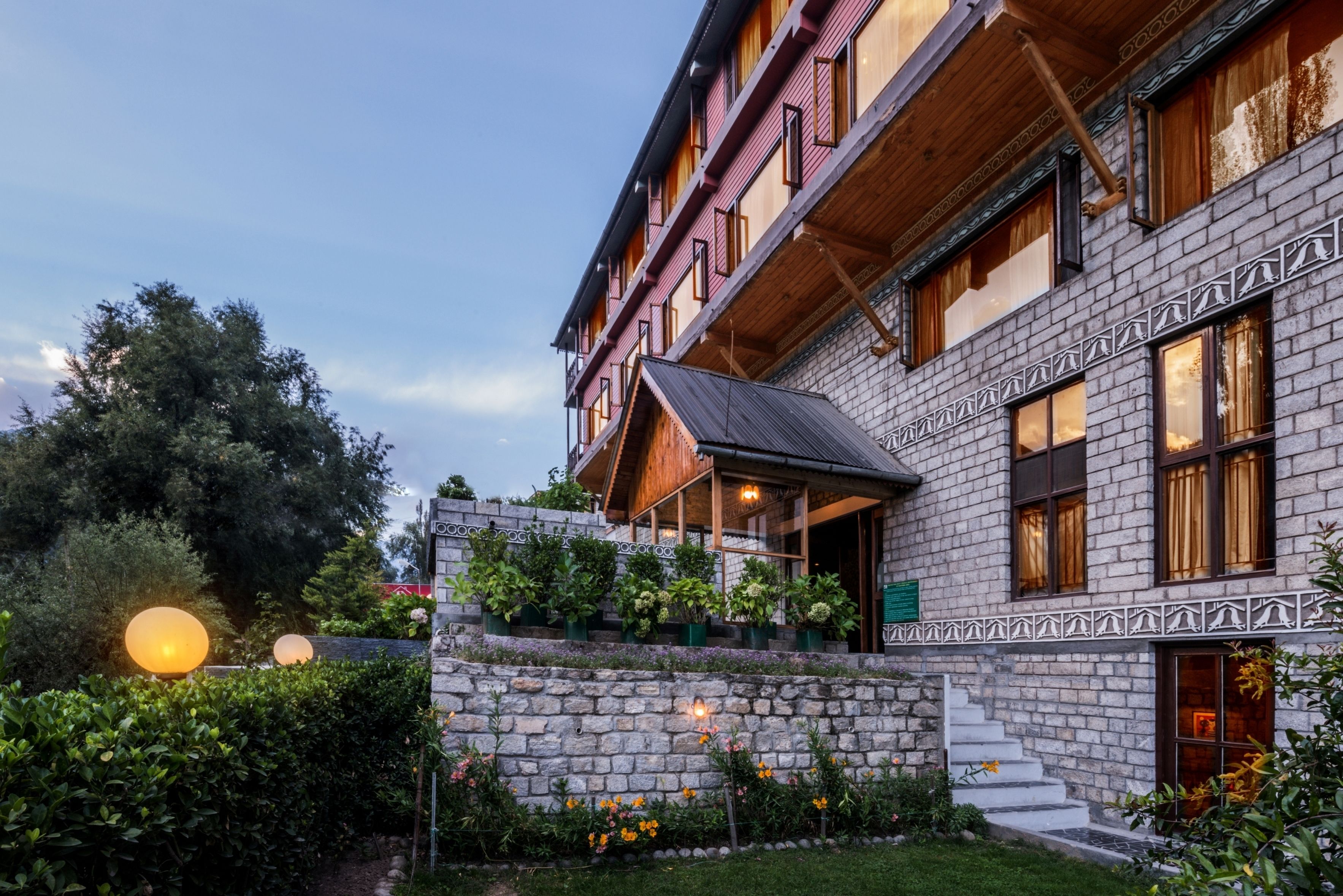 A multi-story building with a stone facade, wooden balconies, and a stone staircase leading to the entrance.