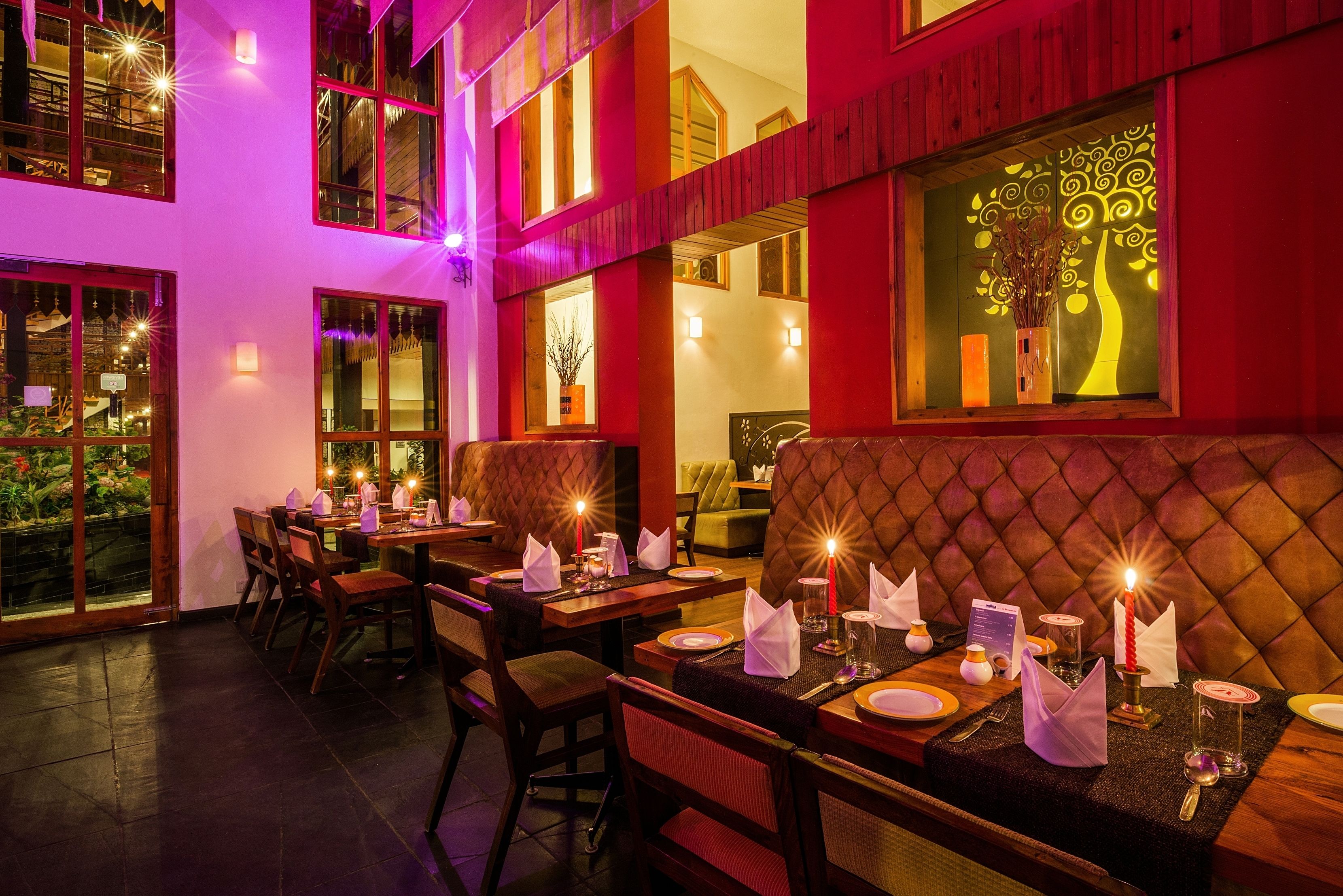 Un restaurant où les tables sont dressées pour le service, avec des sièges confortables et un éclairage décoratif.