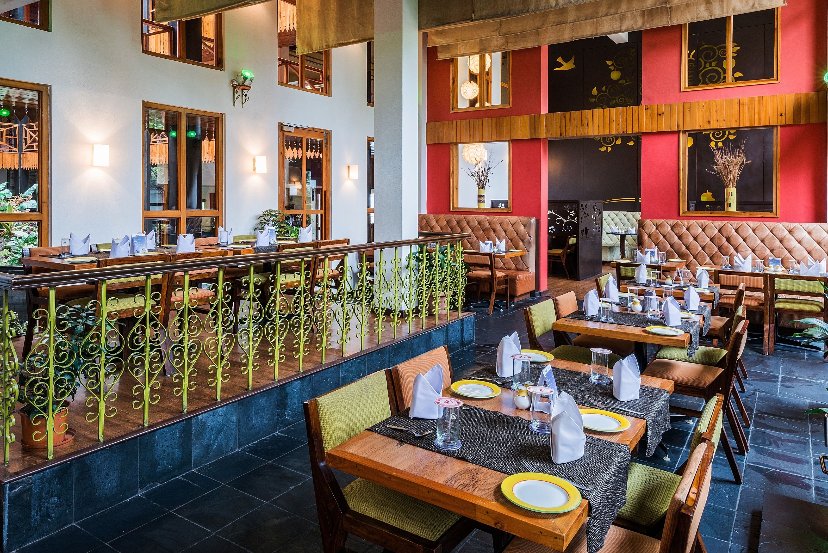 A restaurant with multiple dining tables, cushioned booths, and a decorative railing.