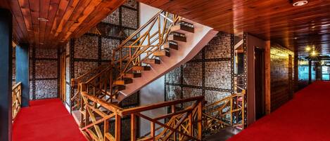 Una escalera de caracol con barandas de madera en una habitación con paredes de piedra y alfombra roja.