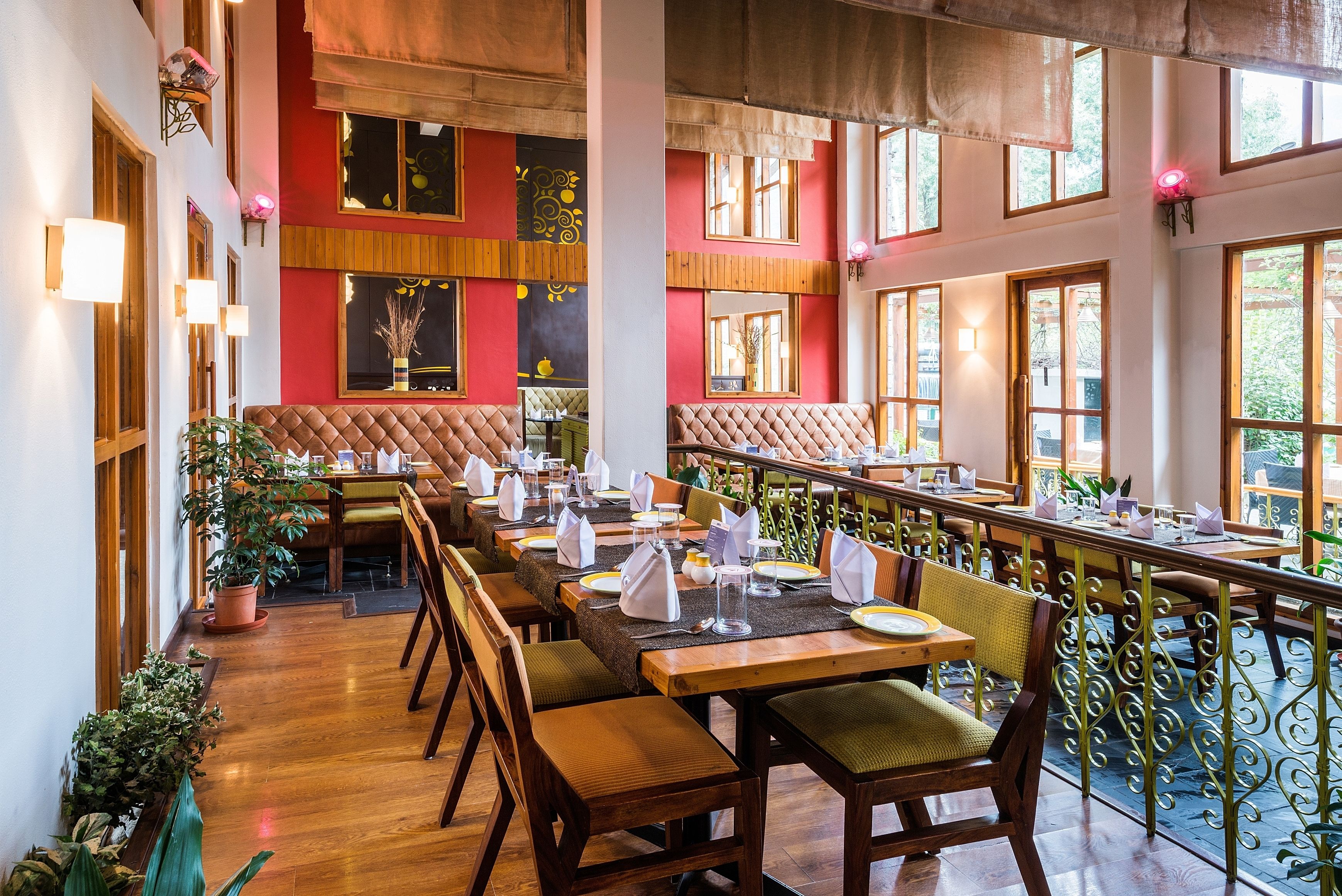 Un restaurant avec de longues tables en bois, des chaises rembourrées et une décoration aux couleurs rouge et blanche.