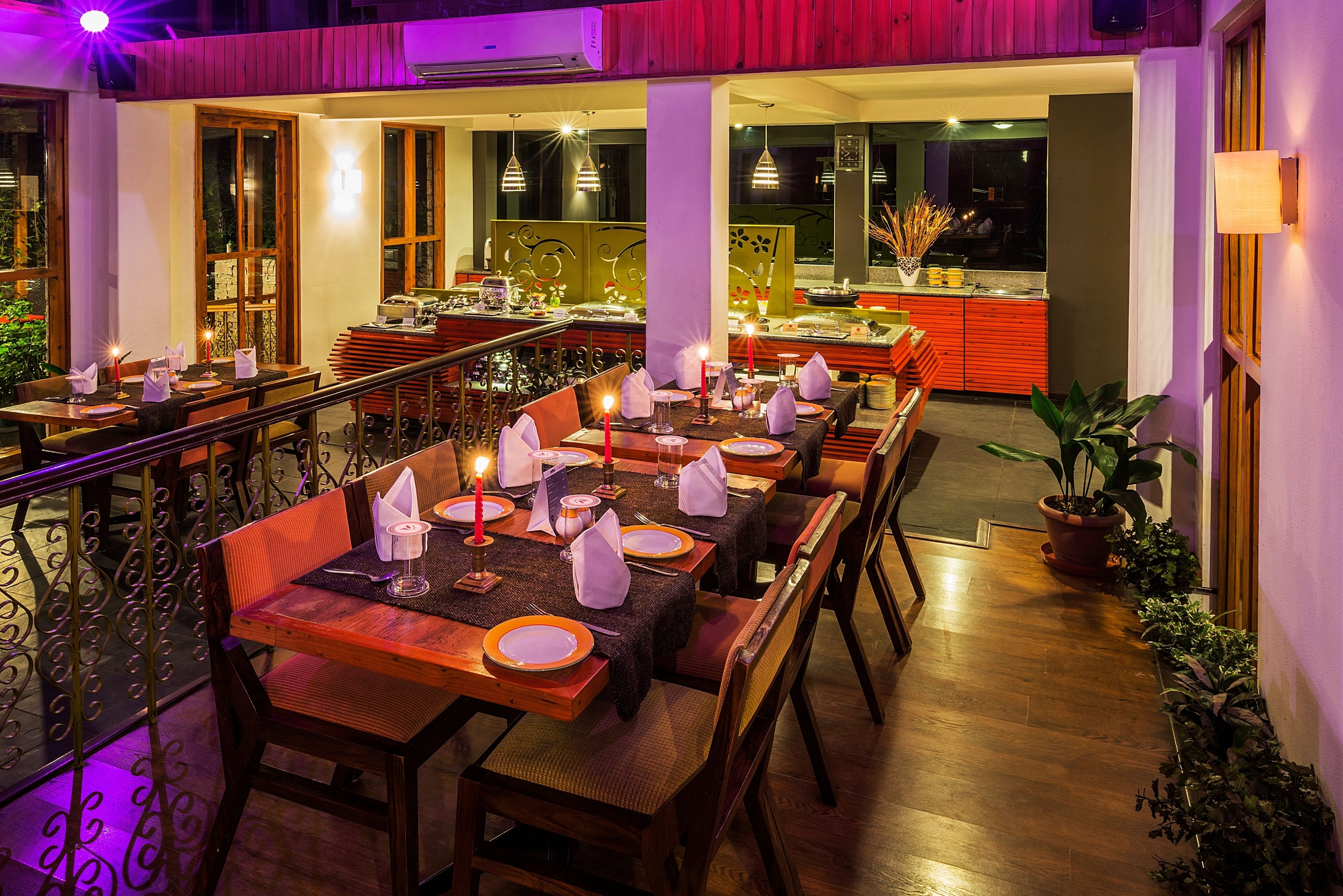 A restaurant with multiple dining tables set for guests, featuring candles and neatly arranged table settings.