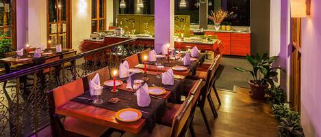 A restaurant with multiple dining tables set for guests, featuring candles and neatly arranged table settings.