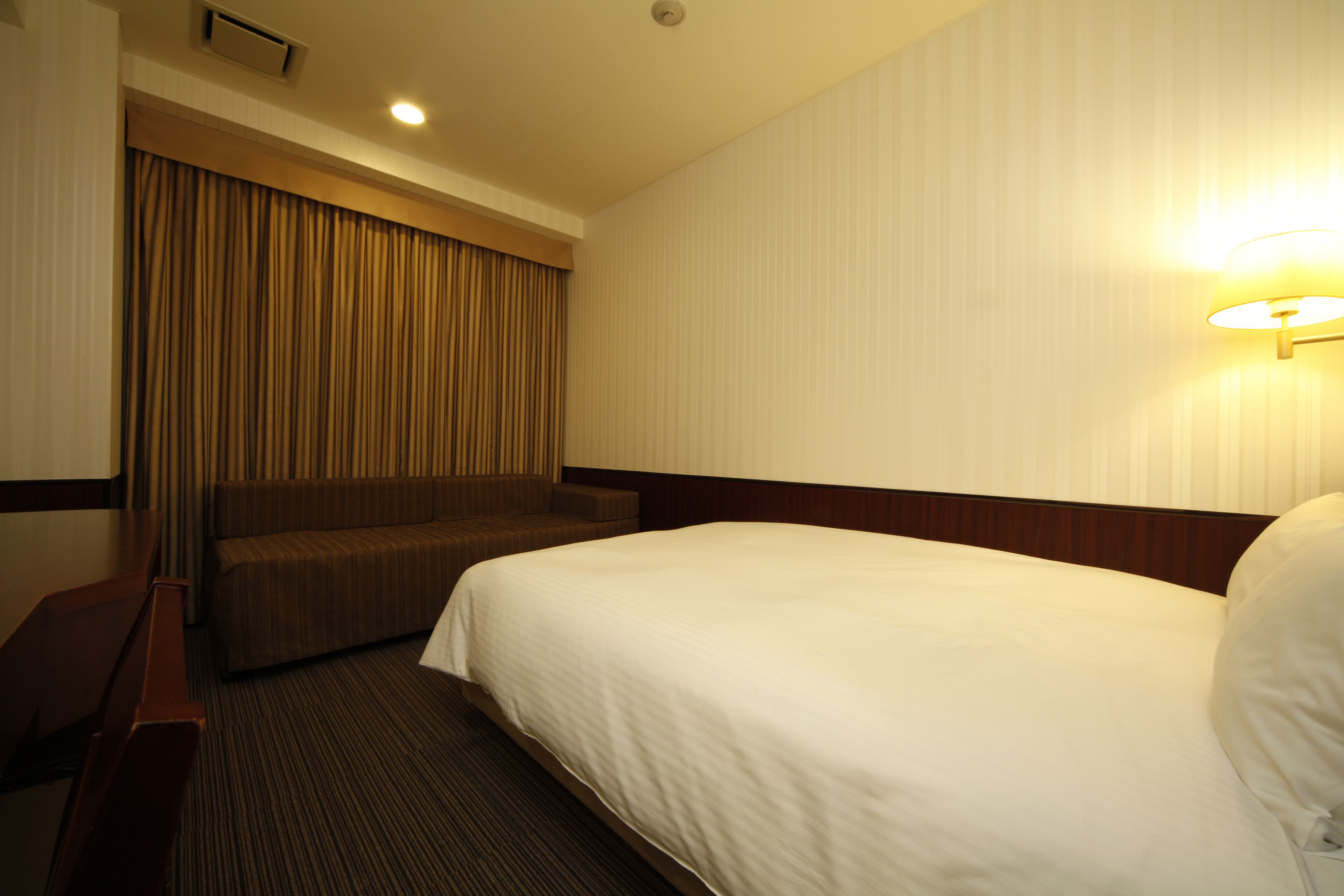 Een hotelkamer met een groot bed, een zithoek en een wandlamp.