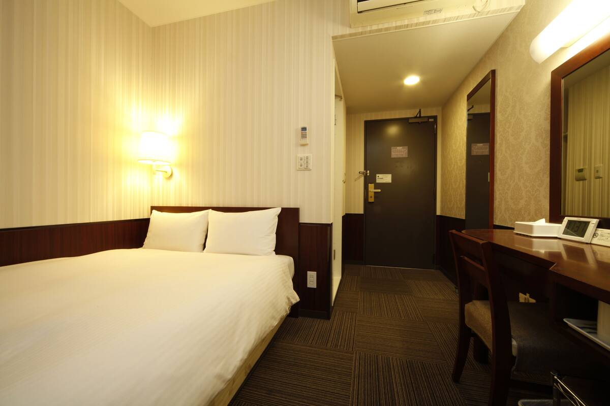 Ein Hotelzimmer mit Bett, Schreibtisch, Stuhl und Spiegel.