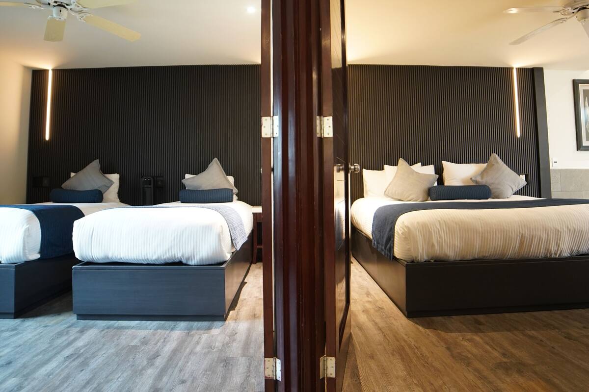 A modern hotel room with a large bed, a smaller bed, and a seating area.
