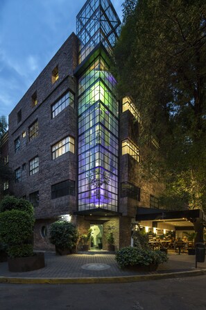 A modern building with a glass facade and brick exterior, featuring a central entrance and surrounding greenery. - FlowSuites Polanco (Mexico City)