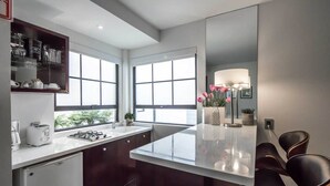 A modern kitchen with a central island, dark cabinetry, and a window providing natural light. - FlowSuites Polanco (Mexico City)