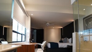 A modern hotel room with a desk, chair, bed, and a glass partition. - FlowSuites Polanco (Mexico City)