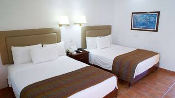 Habitación de hotel con dos camas, cada una con cabecera, mesita de noche con teléfono y un cuadro en la pared.