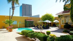 A courtyard with a swimming pool, palm trees, and outdoor seating. - Best Western Saltillo (Saltillo)