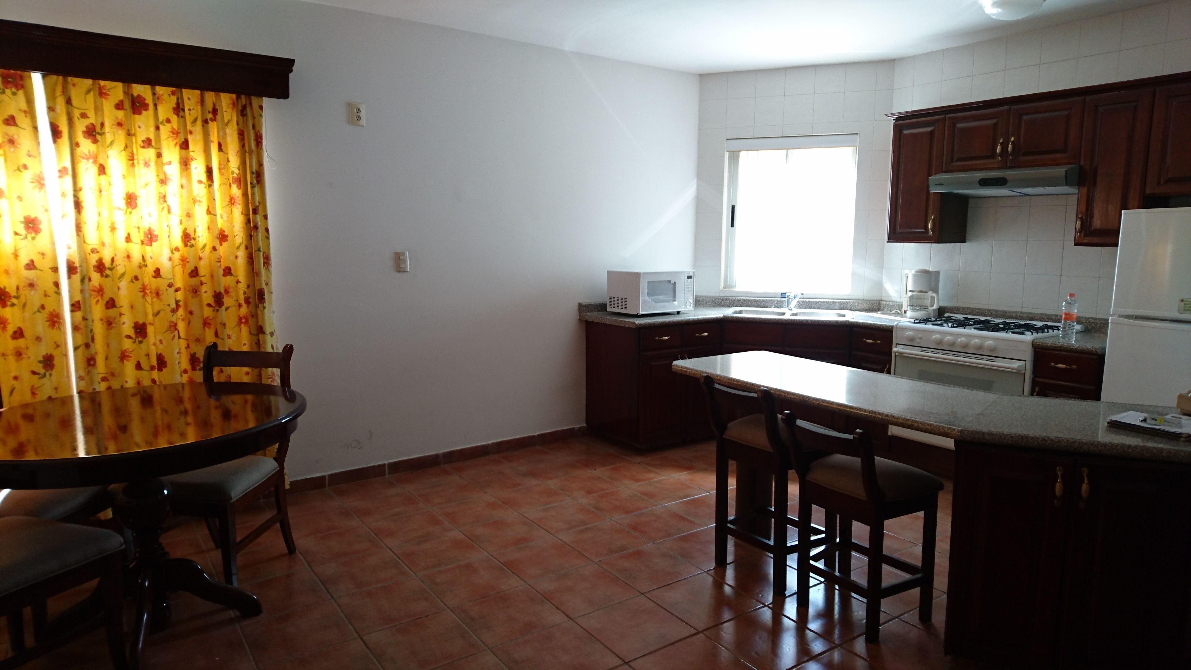 A kitchen with a dining table, chairs, a microwave, stove, and cabinets.