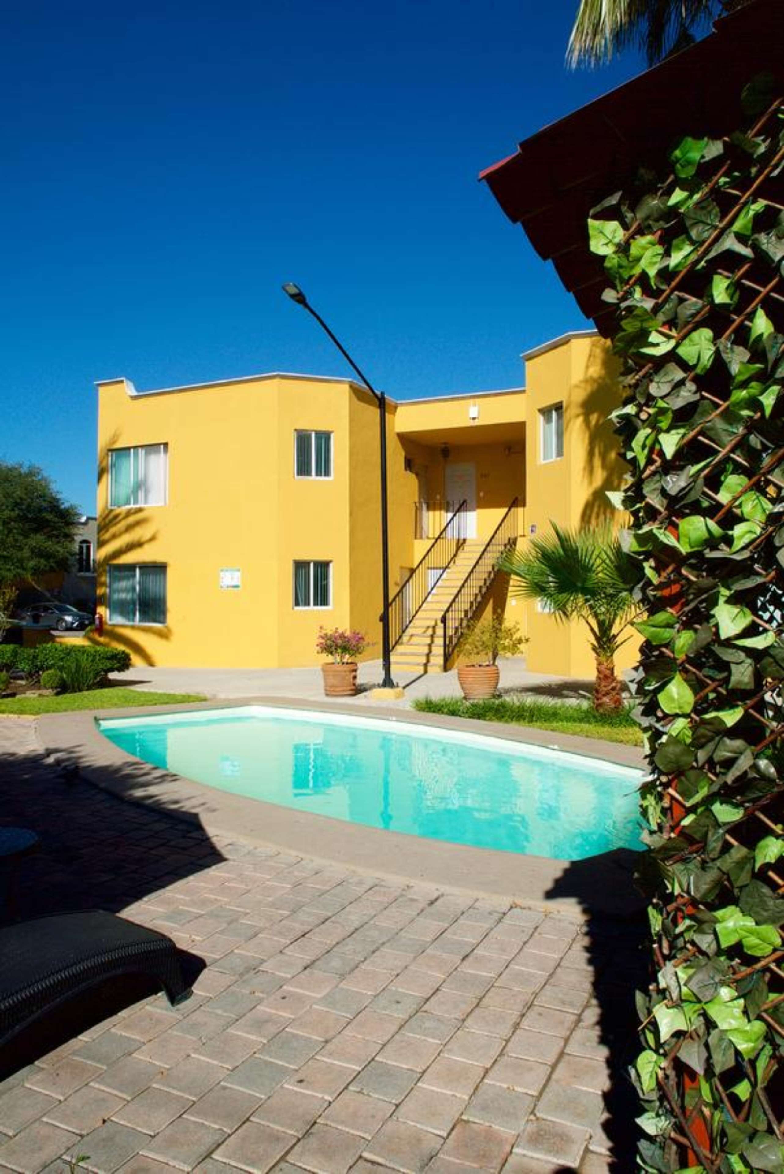 A yellow building with a swimming pool, a staircase, and a street lamp.