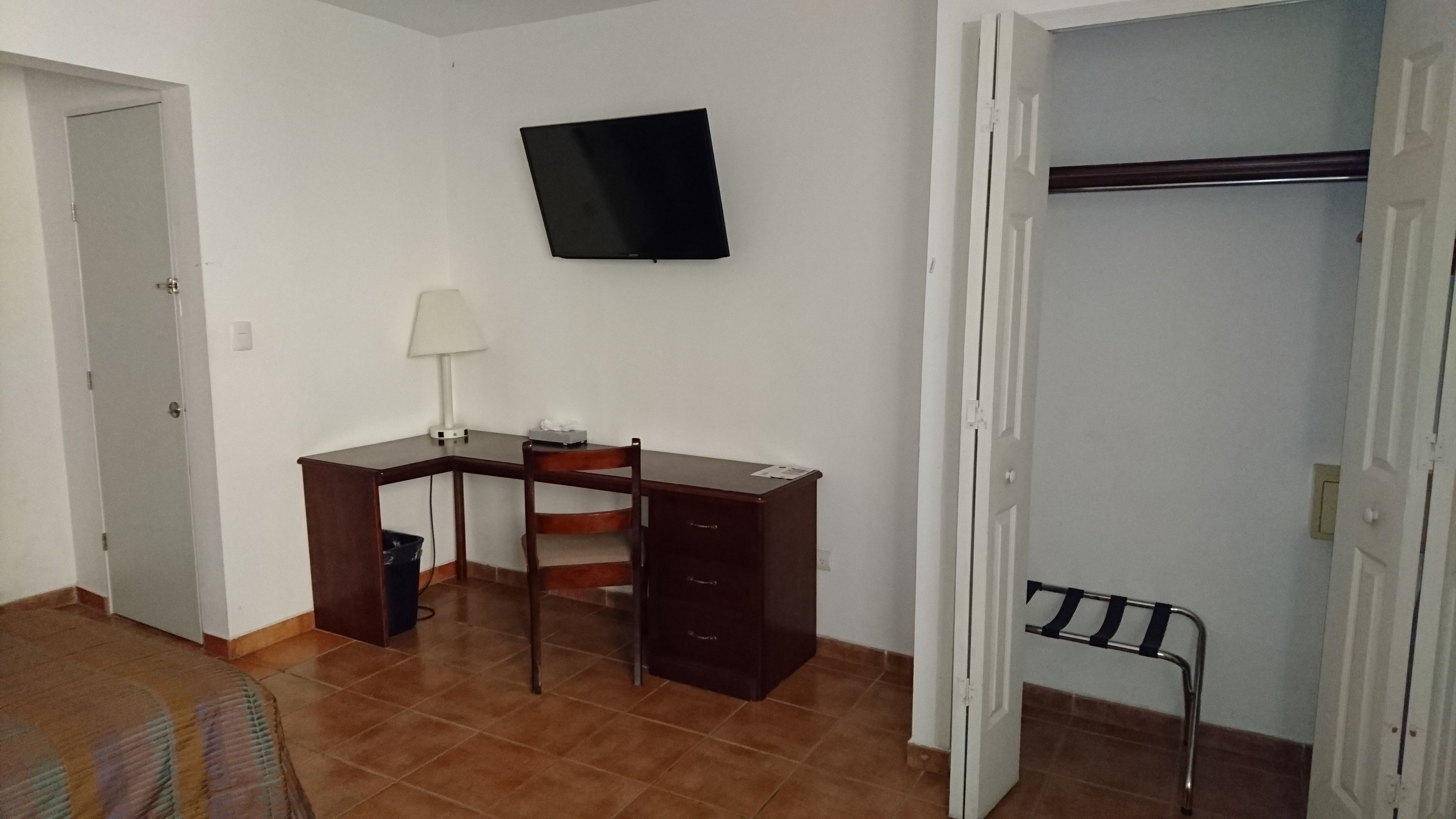 Una stanza con una scrivania, una sedia e un televisore montato a parete.