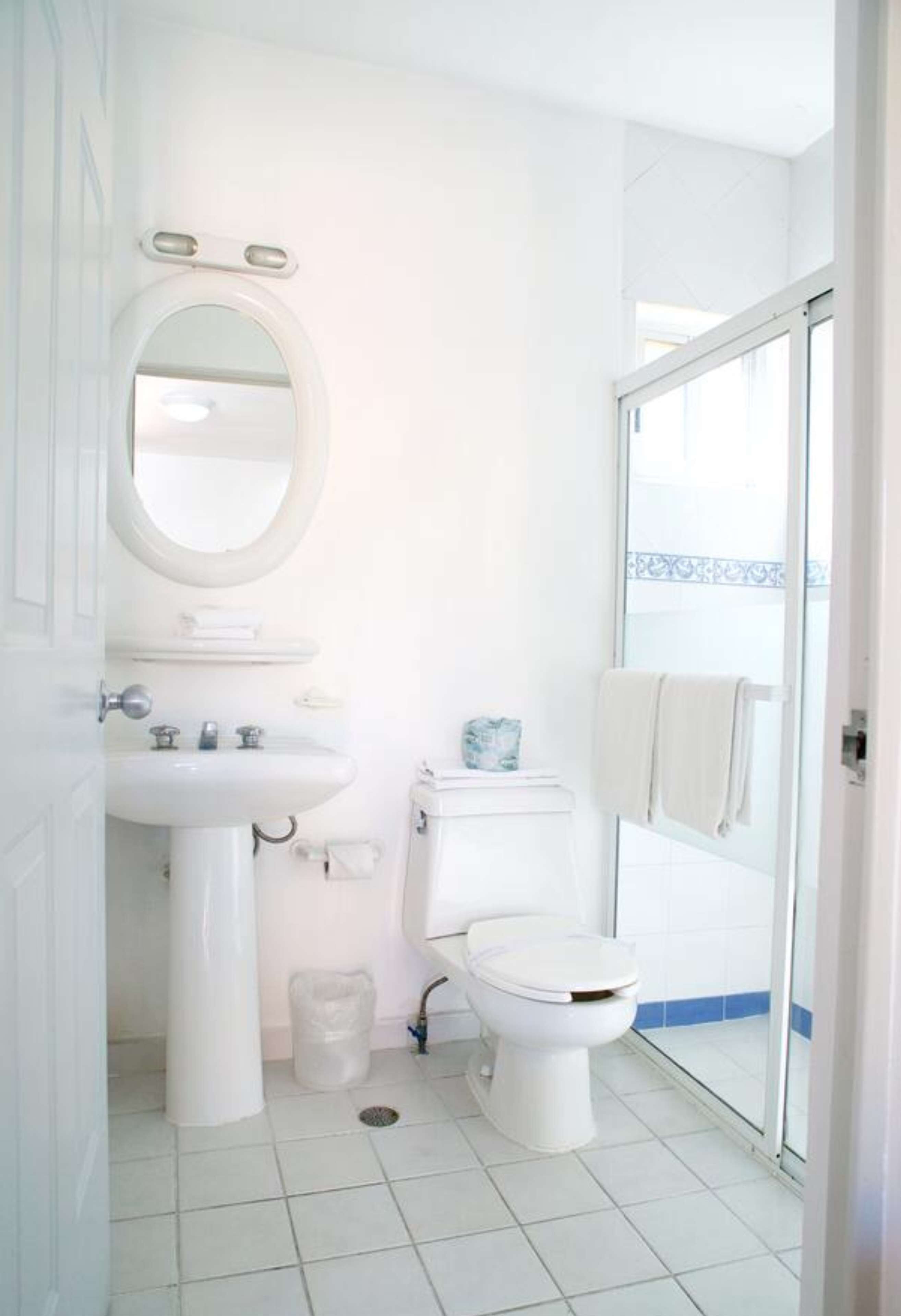 Un bany petit i funcional amb un lavabo, vàter i porta de vidre per a la dutxa.