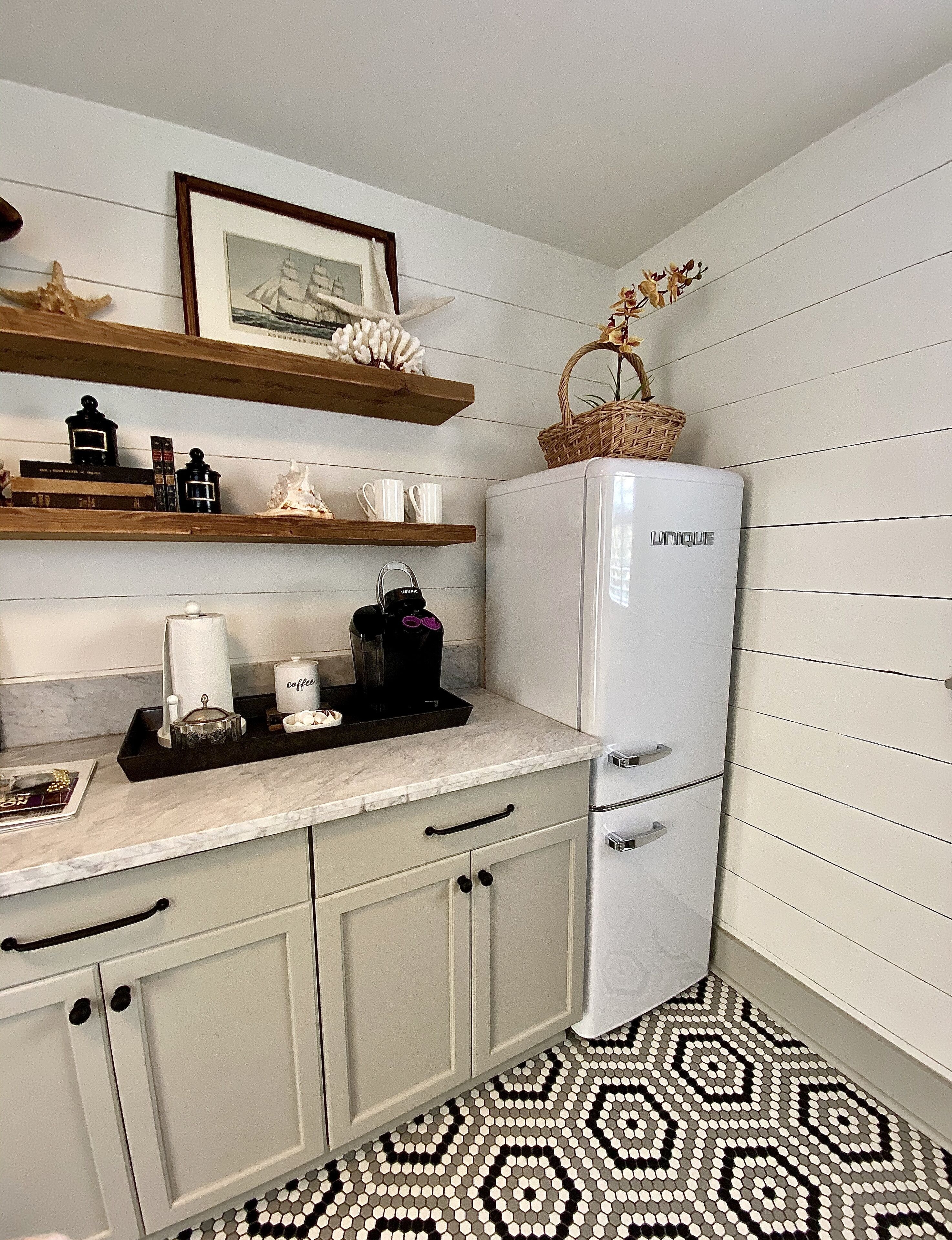 A compact kitchen with a white refrigerator, a coffee maker, and a small countertop with decorative items.