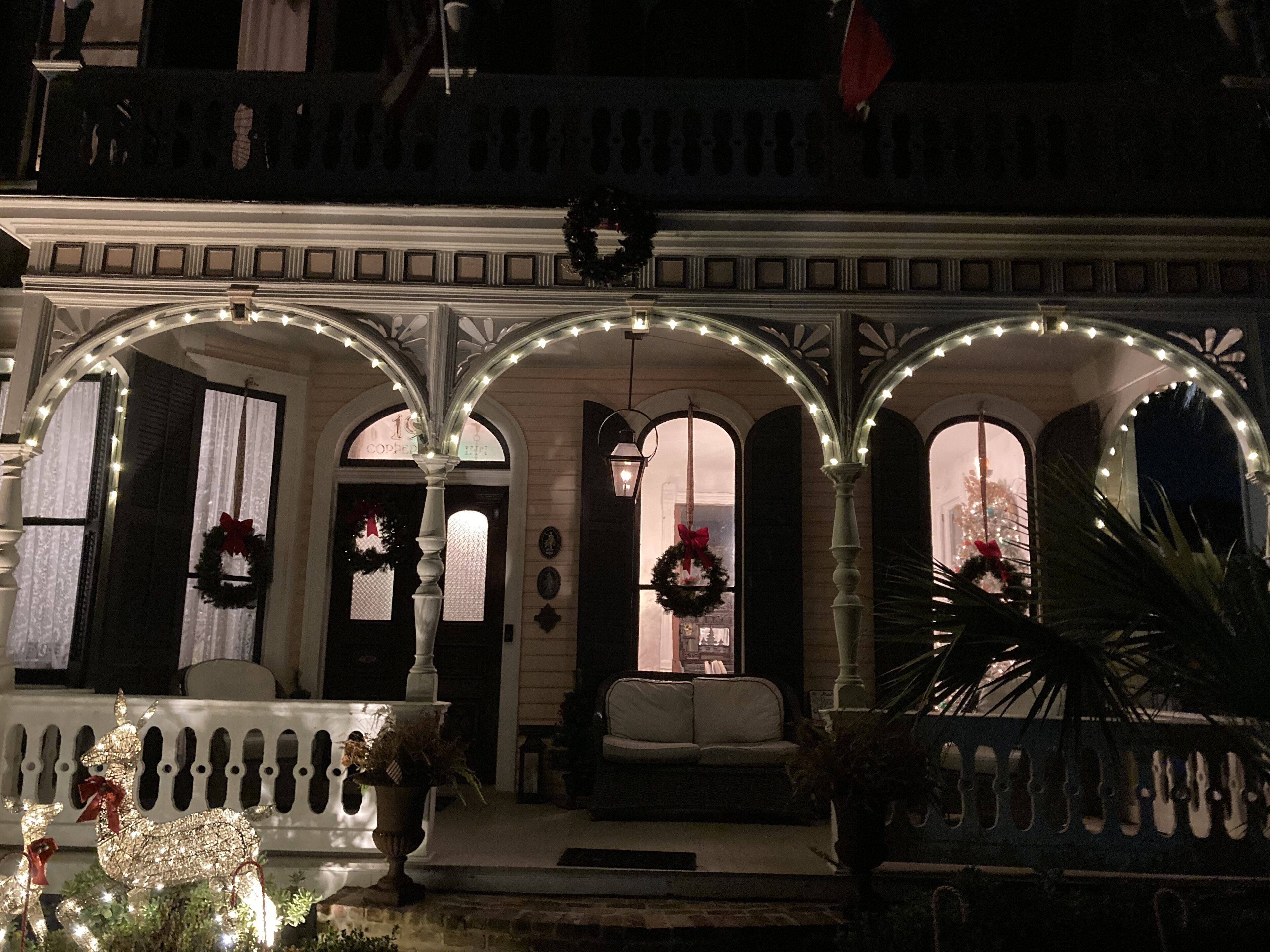 Ein Gebäude mit einer Veranda, einem weißen Geländer und einem Weihnachtskranz.
