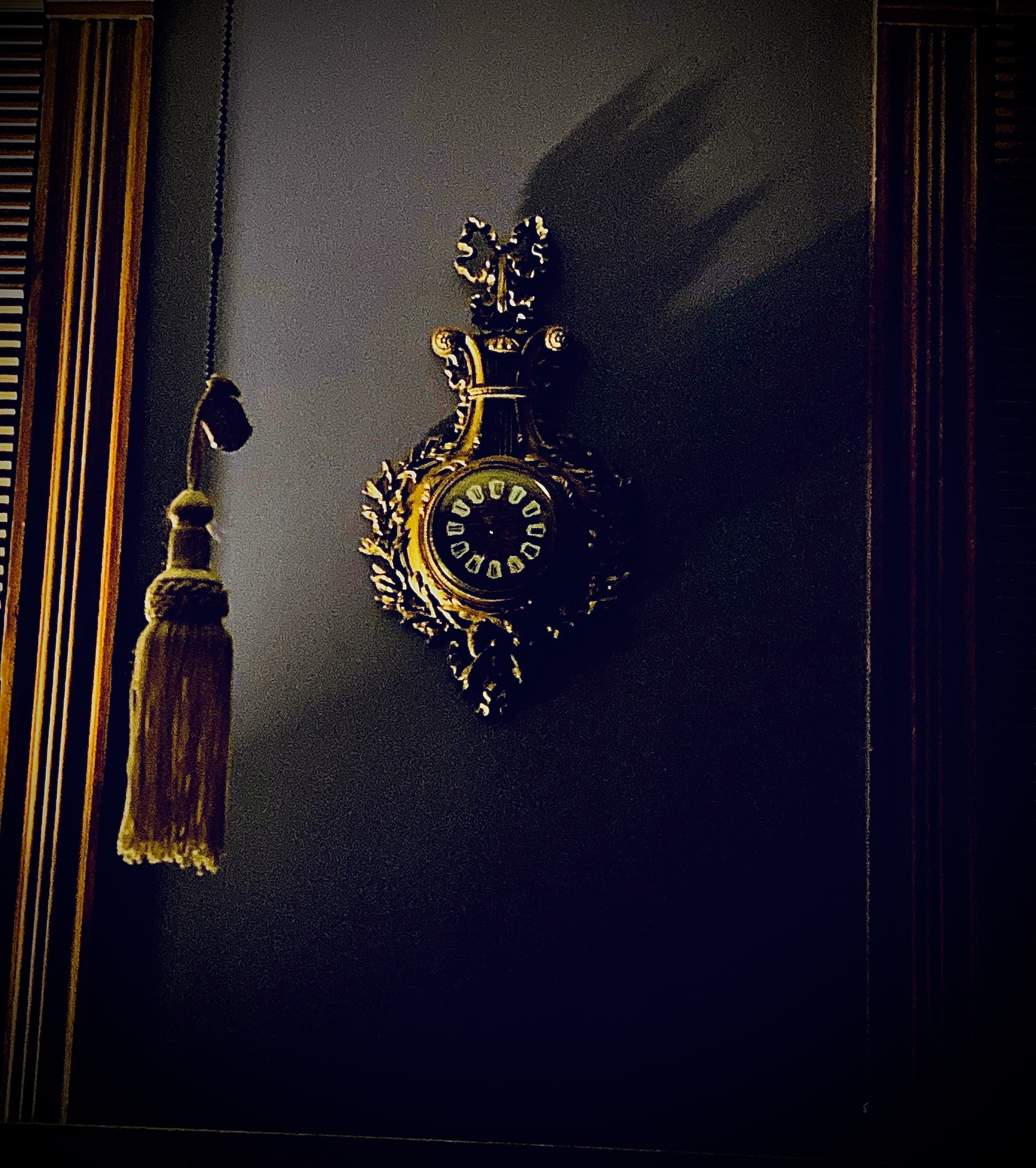 Une porte noire ornée d’une horloge dorée et d’une frange qui y est suspendue.