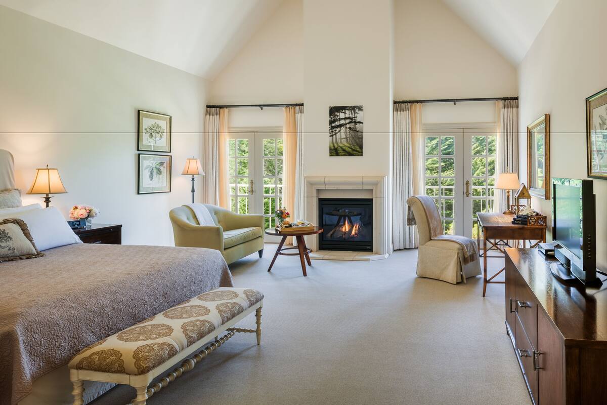 A spacious bedroom with a large bed, a fireplace, and a television.