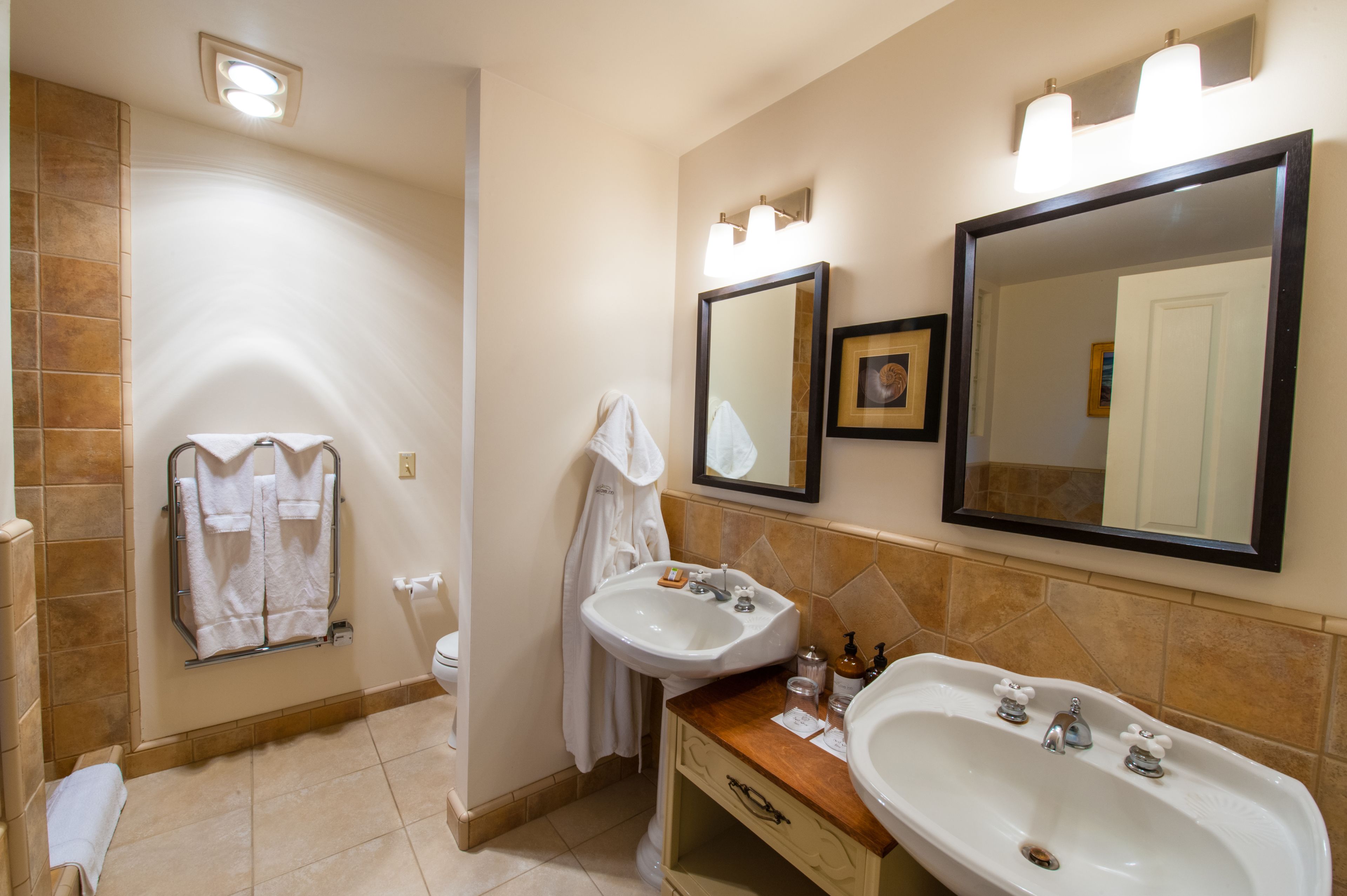 Une salle de bain avec deux lavabos, des toilettes et un porte-serviettes.