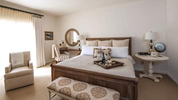 A neatly arranged bedroom with a large bed, bedside tables, a chair, and a bench.