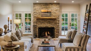 A cozy living room with a stone fireplace, comfortable seating, and a bookshelf. - Seal Cove Inn (Moss Beach)