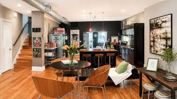 Una cocina moderna con comedor, una escalera y una sala de estar con chimenea.