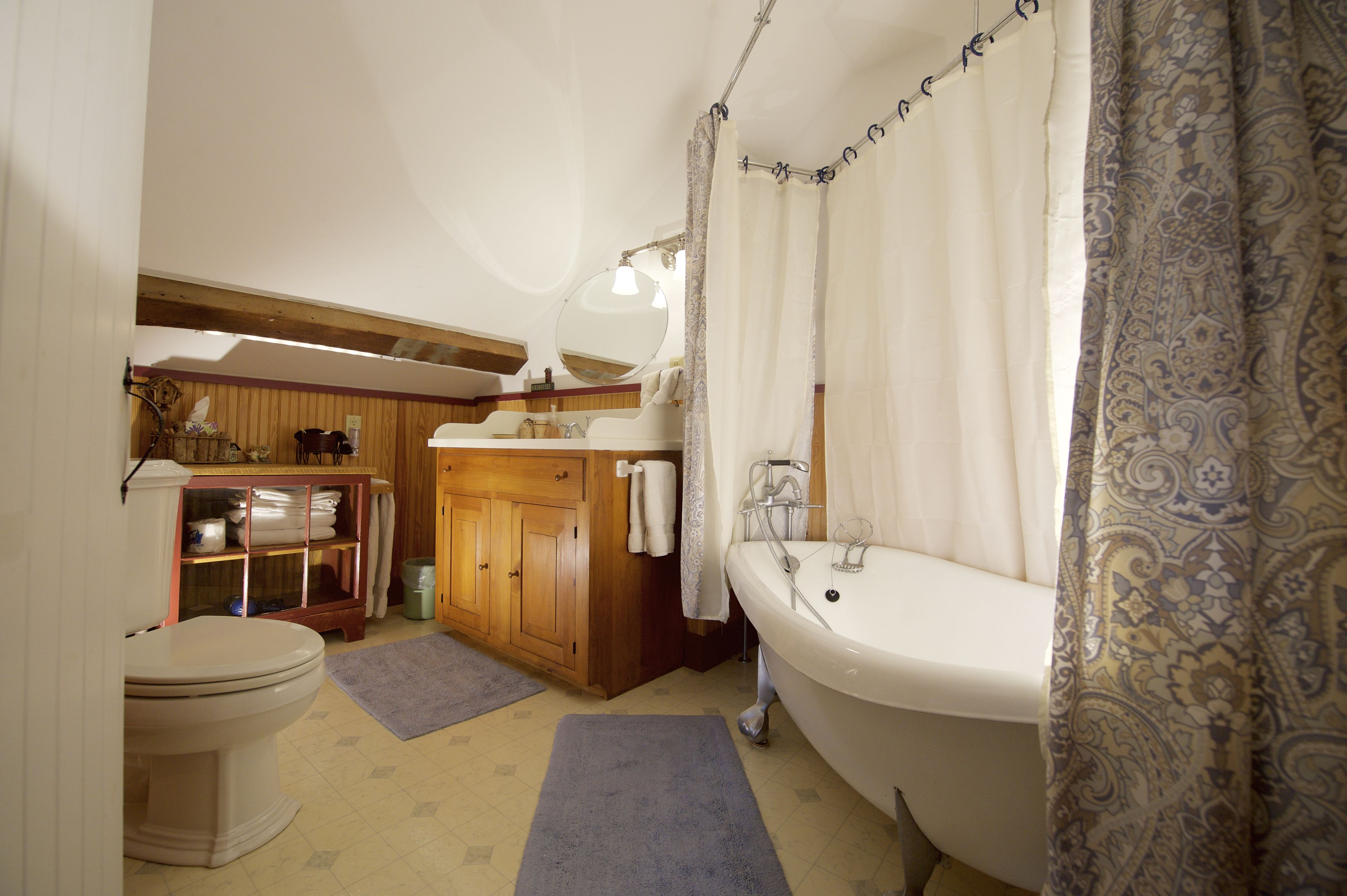 Un baño con inodoro, un armario de madera, un lavabo y una bañera.