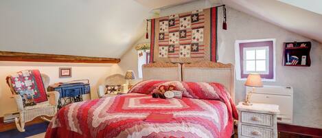 Ein Schlafzimmer mit einem großen Bett, einem Deckenventilator, einem gepolsterten Wandbehang, einem kleinen Tisch mit einer Lampe und einer Heizung.