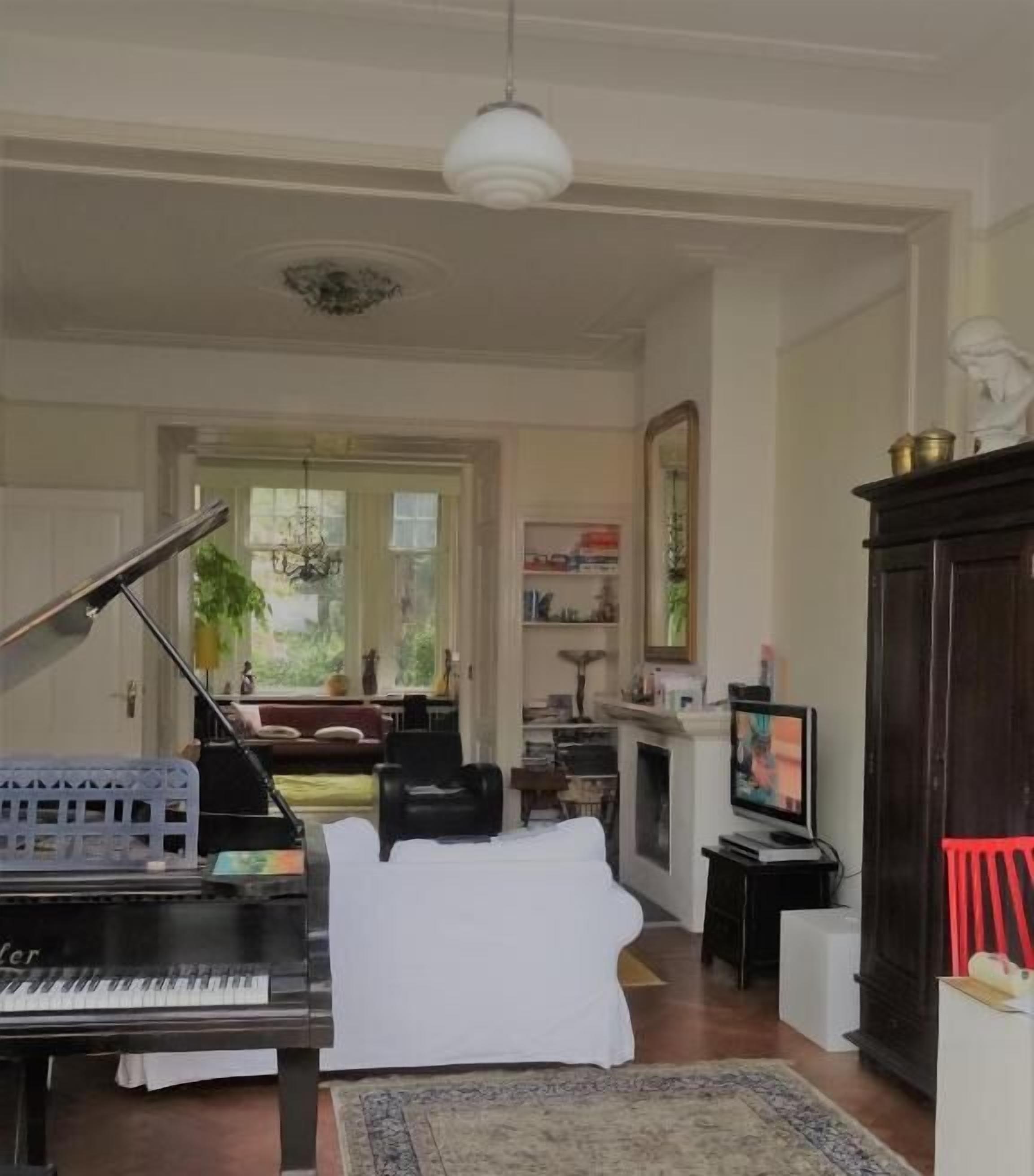 Un salón espacioso con un piano de cola, un televisor y una chimenea.