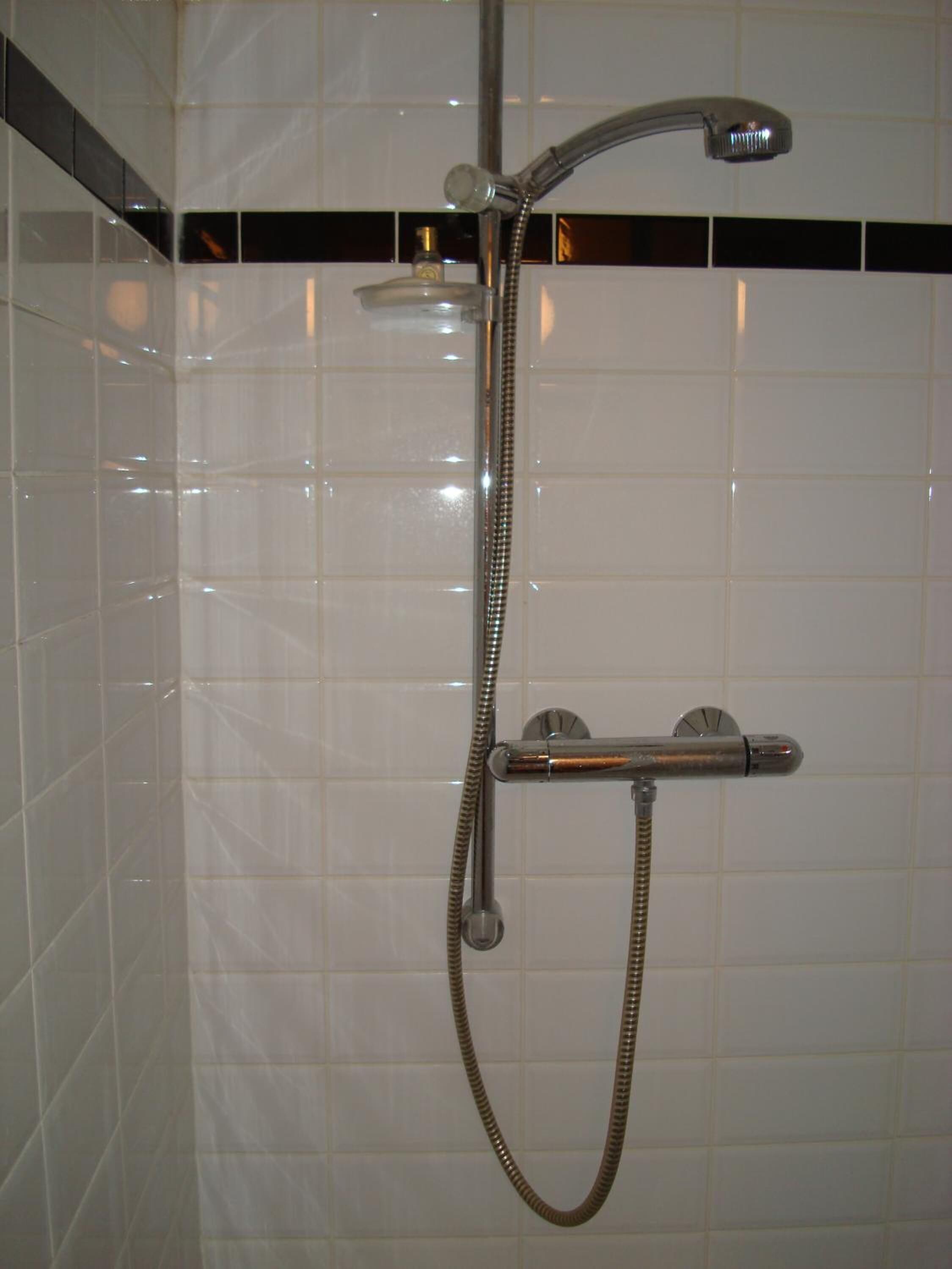 Ducha con cabezal de ducha de mano y llave fija en la pared.