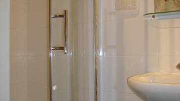 Un baño con cabina de ducha de vidrio, un lavabo blanco y un espejo sobre él.