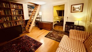 Ein gemütliches Wohnzimmer mit einer Holztreppe, einem Bücherregal, einer Couch und einem Esstisch.