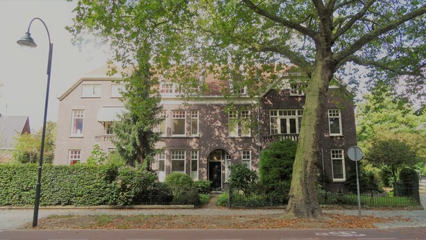 Ein zweistöckiges Gebäude mit Backsteinfassade, großen Fenstern und einem markanten Eingang.