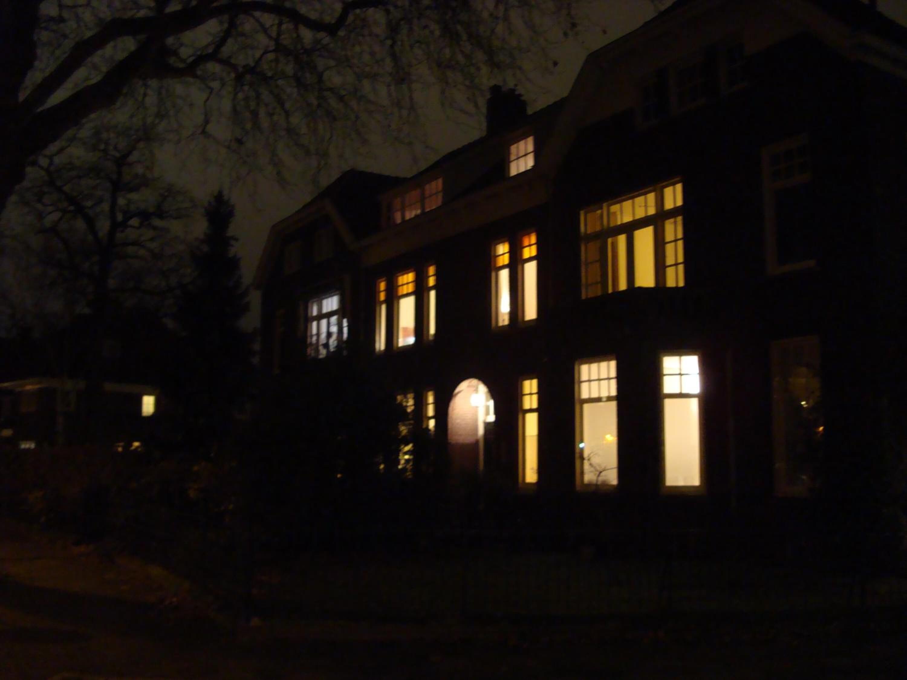 Un edificio grande de varios pisos con ventanas iluminadas en la noche.