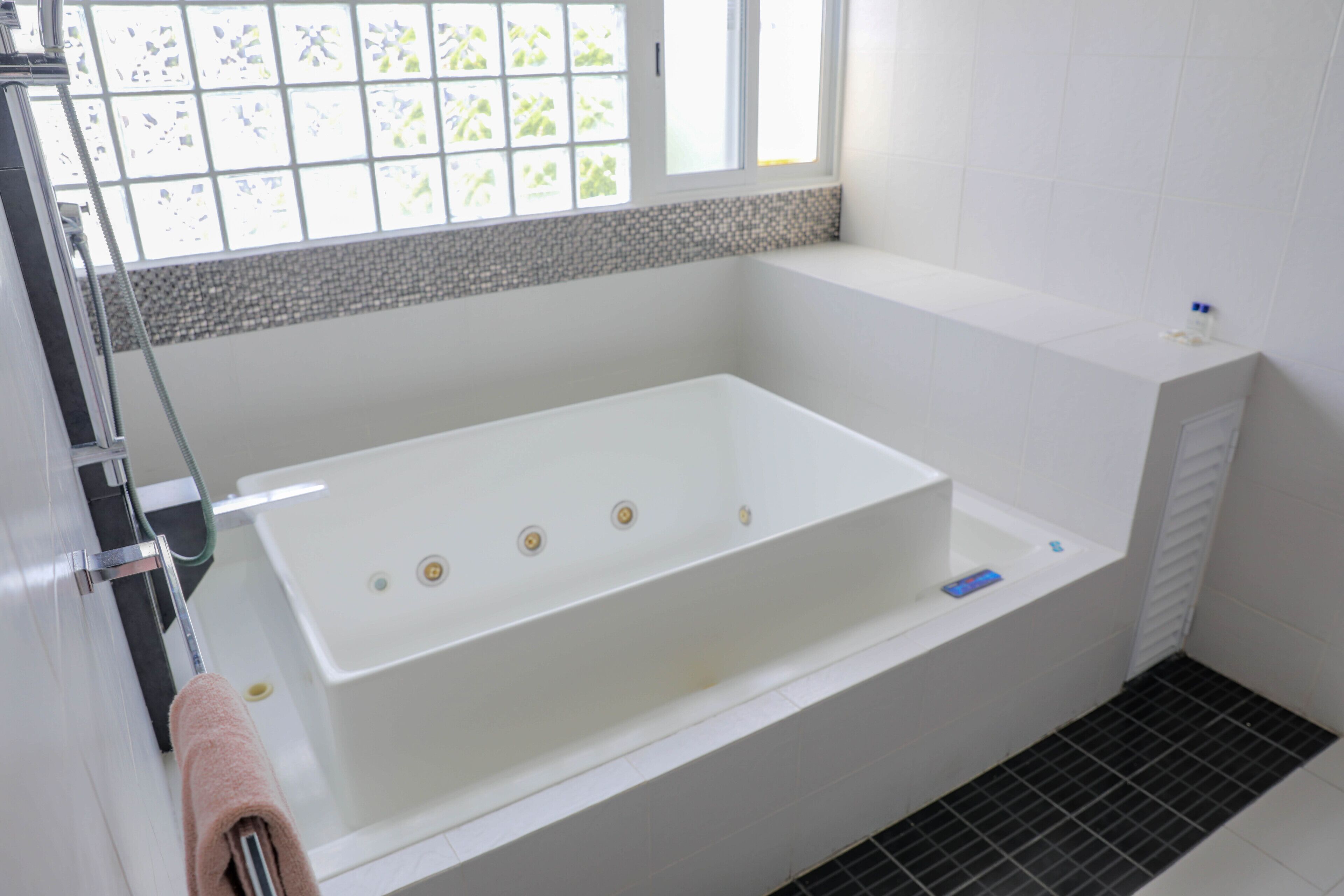 Un baño moderno con una bañera blanca grande, zona de ducha y ventana con vistas al exterior.