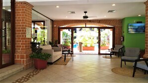 A hotel lobby with a reception desk, seating area, and a pool view.