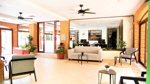 A spacious lobby with a sofa, chairs, a coffee table, and potted plants.