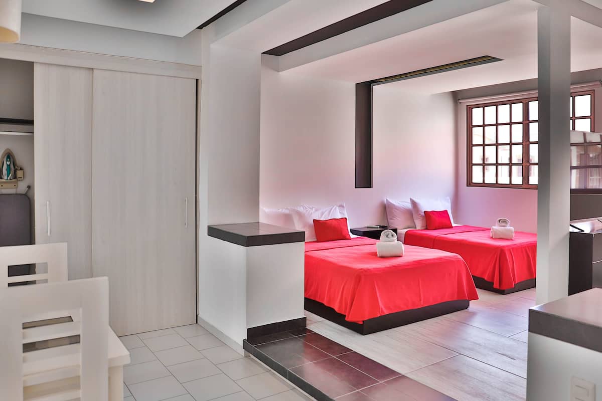Una habitación de hotel moderna con dos camas, un armario, un escritorio y una ventana con persianas.