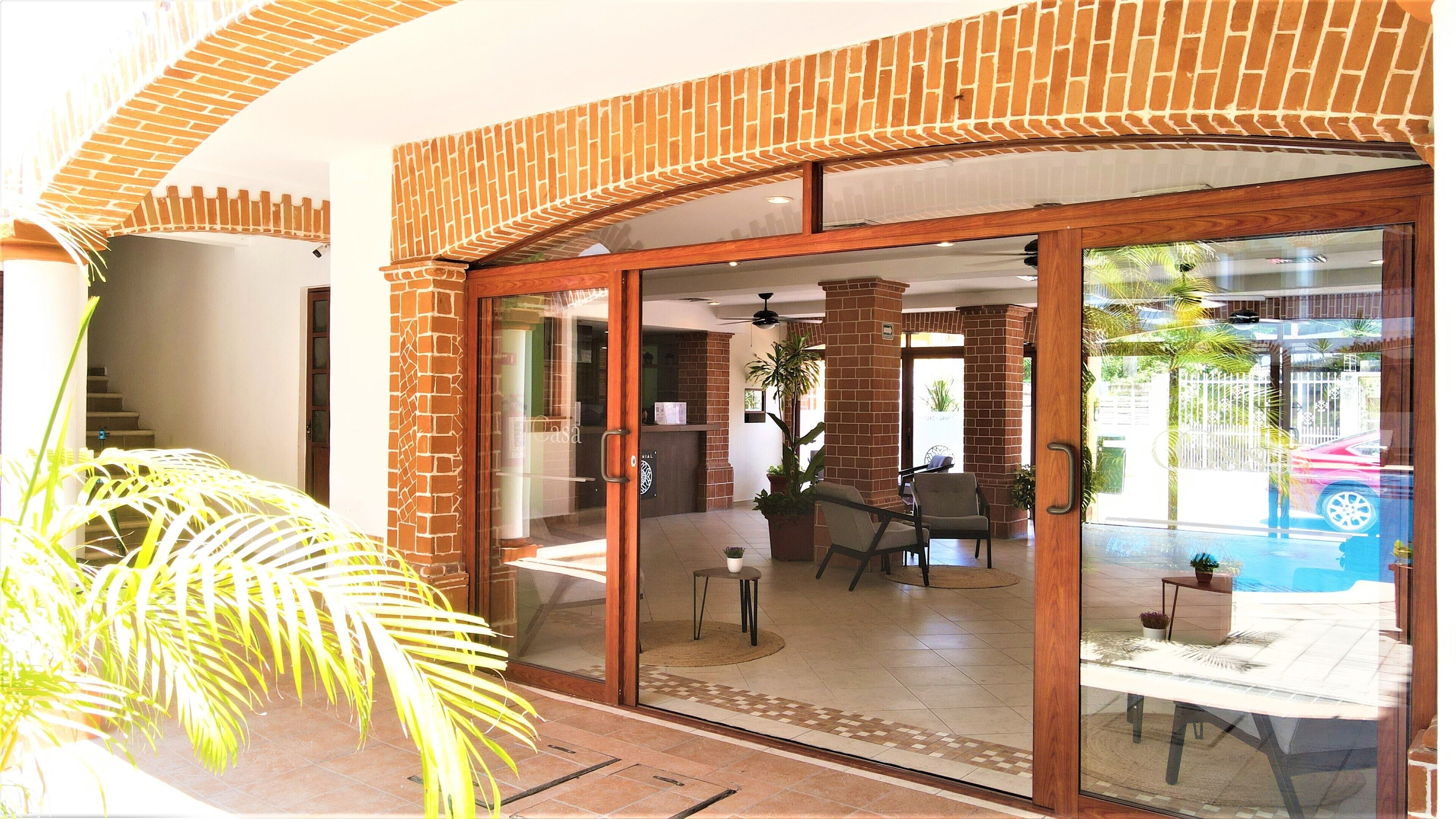 A spacious indoor area with a glass door leading to a pool, surrounded by brick walls and a ceiling fan.