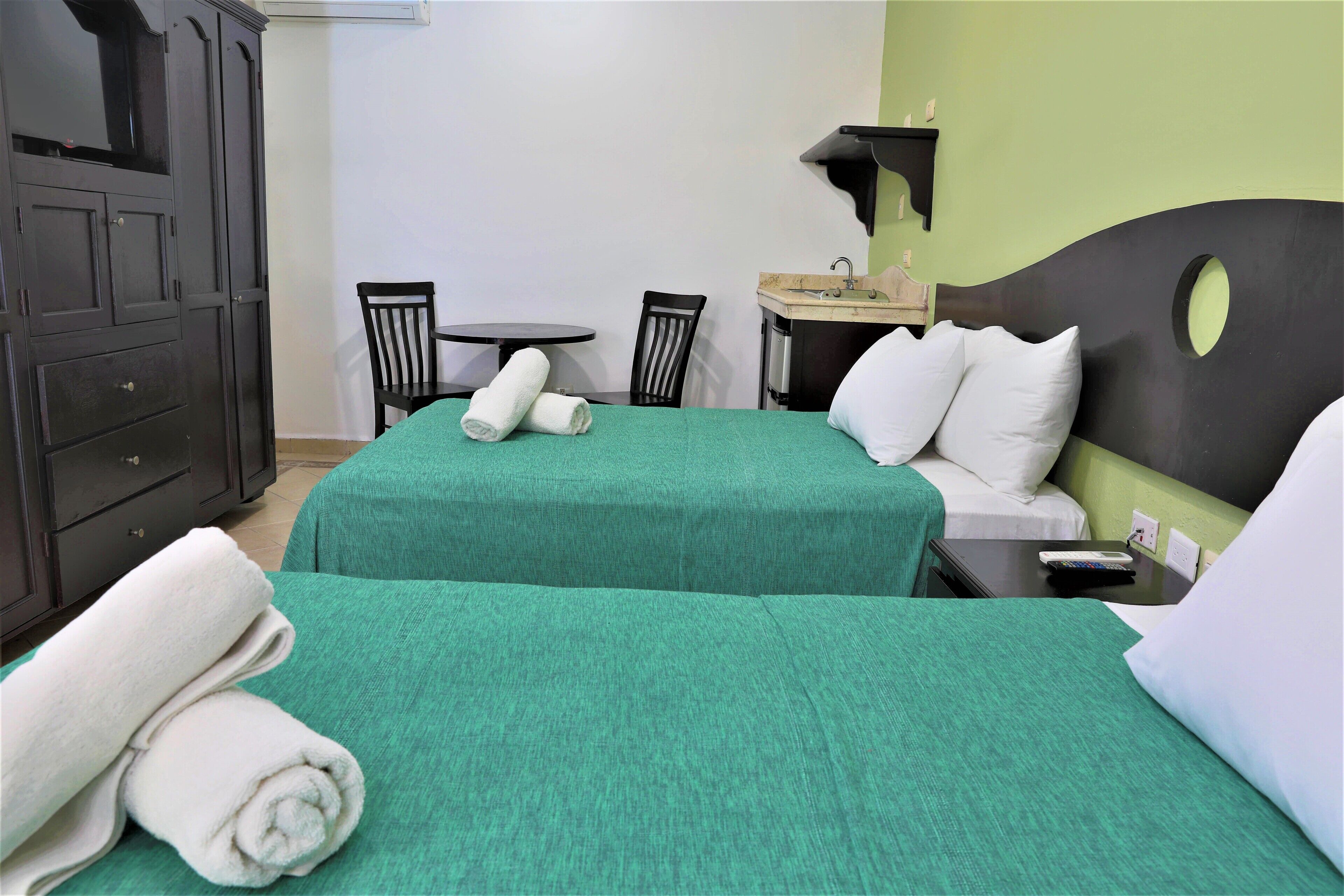 Une chambre d’hôtel avec deux lits, un bureau, une chaise et une armoire.