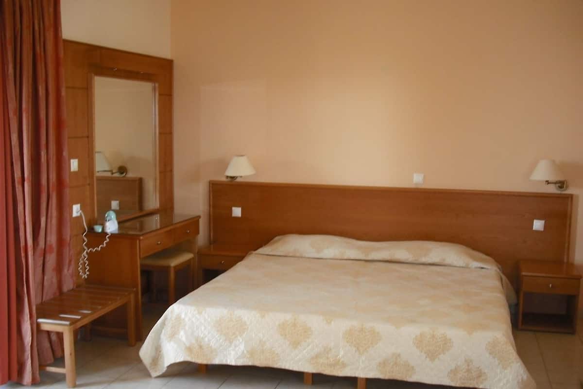Een slaapkamer met een houten bed, nachtkastjes, een spiegel en een bureau.