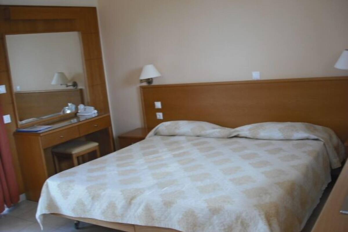 Hotelkamer met een bed, een bureau, een stoel, een spiegel en twee bedlampen.
